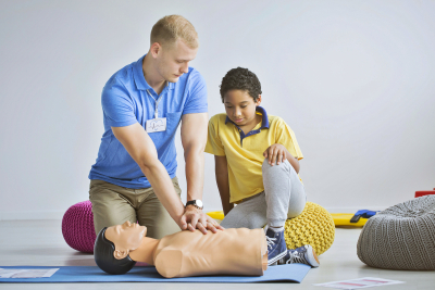first aid exercises on a manikin to a boy