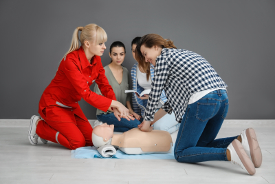 group of people practicing cpr on mannequin at first aid class