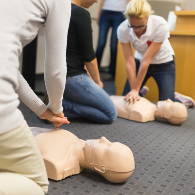 group of students performing cpr chest compressioon on a dummy